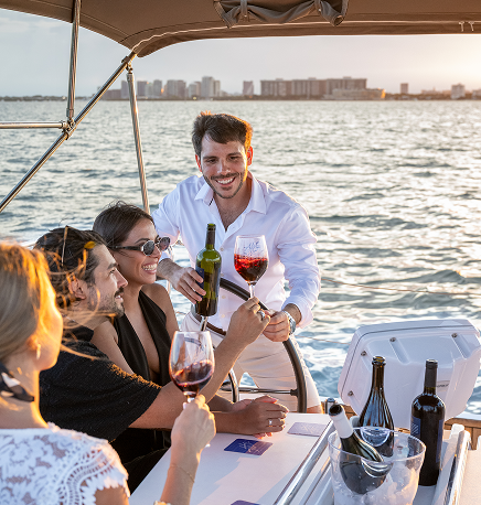A sommelier pouring red wine for seated guests aboard