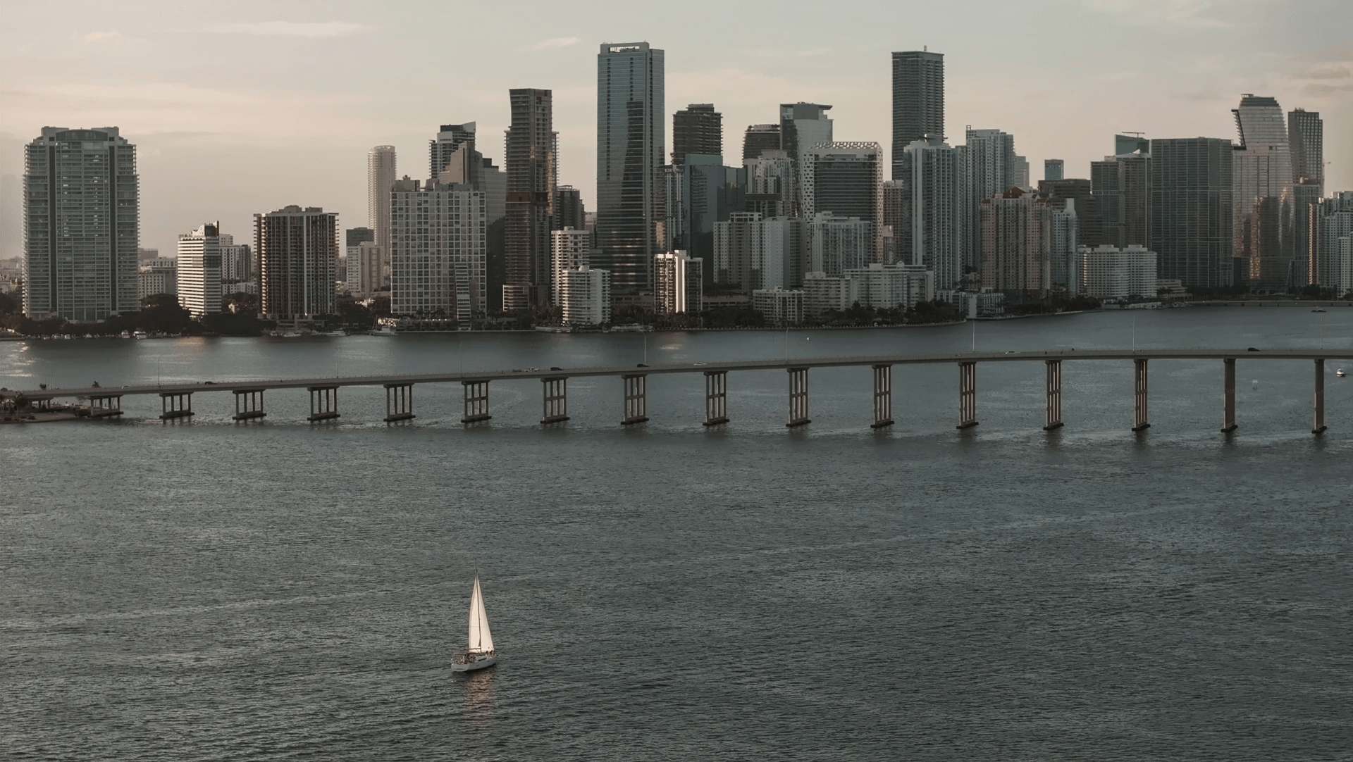 The Miami skyline and Biscayne Bay seen from the water, a sailboat in the distance